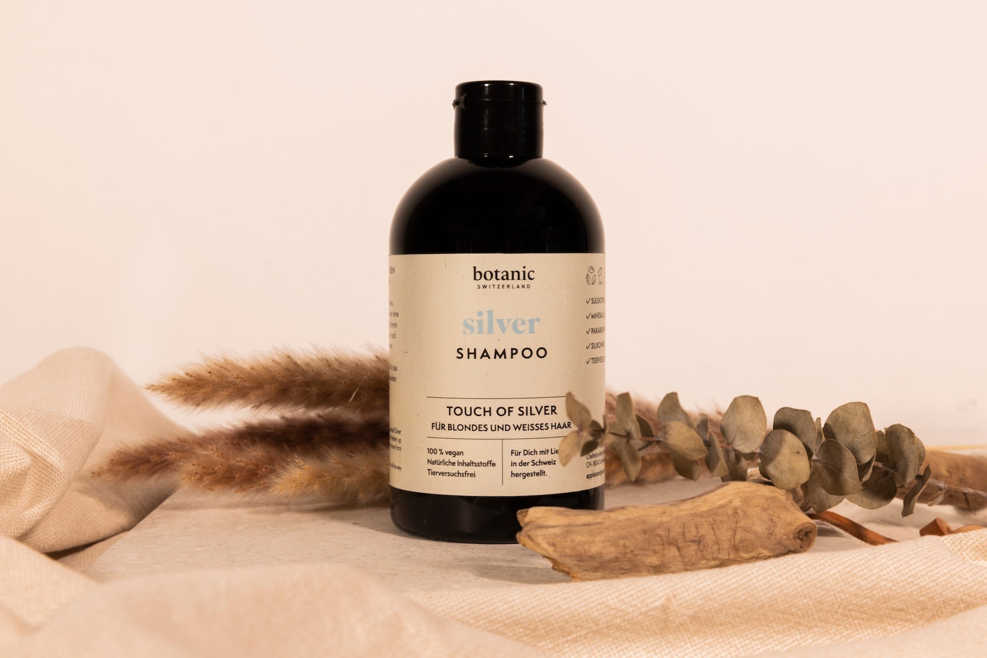 Eine Flasche Silver Shampoo von Botanic Switzerland, im Hintergrund Dekoration