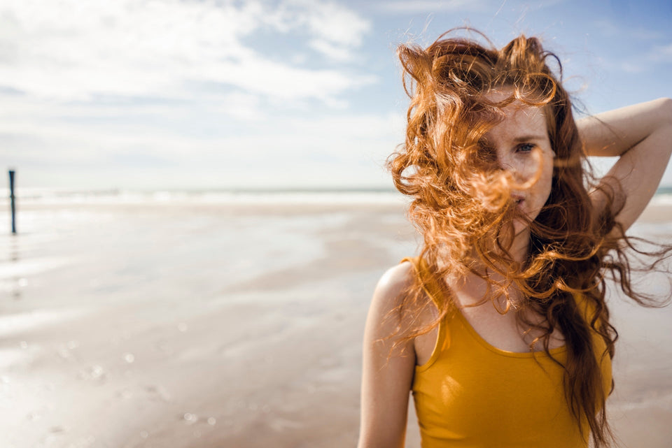 Eine Frau mit roten Locken am Strand