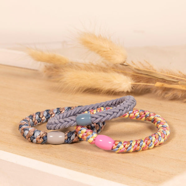 Drei Haargummis liegen auf einem Holzbrett