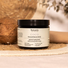 Botanic Switzerland Coco Haarmaske neben einer Kokosnuss